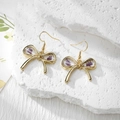 Detailed close-up of bow earrings with real purple dried flowers in resin and gold metal hooks - Stainless Steel Earring Hook / Purple Leaf Large Bow