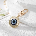 Macro detail of Evil Eye keychain with golden lobster clasp and blue crystal inlay - Gold Hollow Round Eye