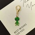 Detail eines grünen Alien-Anhängers mit goldenem Karabiner auf einer weißen Karte - Grüner Alien Großer Hummerverschluss