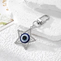 Macro detail of star-shaped evil eye keychain with white crystals on stone surface - Silver Star Eye