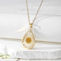 Macro shot of a teardrop resin pendant featuring a real white daisy and gold chain - White Daisy