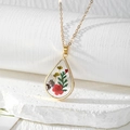 Detailed macro view of teardrop resin pendant featuring real colorful dried flowers - Red Flower Green Leaves with Purple Yellow Baby's Breath
