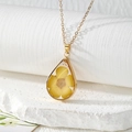 Close-up of a drop-shaped resin pendant with a yellow flower and gold metal frame - Yellow Five-Petal Flower