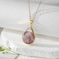 Detailed view of teardrop resin pendant with real pink dried flowers on stone base - Purple Daisy