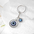 Macro detail of silver Evil Eye keychain with blue enamel and rhinestones on stone - Silver Hollow Round Eye