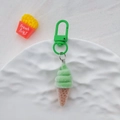 Detailed view of green flocked ice cream keychain with plastic hook on white textured tray - Green Sweet Cone