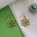 Dettaglio di orecchini a fiocco di neve fatti a mano con cornice d'oro e fiori veri - Fiocco di neve con gipsofila verde e bianca