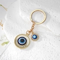 Detail of golden Evil Eye keychain with sparkling crystals and blue enamel charms on stone - Gold Hollow Round Eye