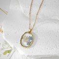 Détail du collier doré élégant avec de vraies fleurs séchées en pendentif résine ovale - Deux fleurs bleues avec gypsophile blanche