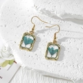 Detail of square gold earrings featuring blue dried flowers in transparent resin - Blue Flower (Stainless Steel Hook)