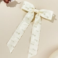 Detail einer eleganten beigen Satin-Haarspange mit Kunstperlen und Rüschenkanten - Beige