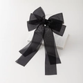 Detail einer eleganten schwarzen Organza-Schleife mit langen Bändern auf Marmor - Schwarz