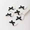 Detalle de pinzas para el pelo con alas de ángel brillantes y lazos negros sobre piedra - Negro