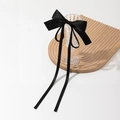 Elegant black silk satin bow hair clip with long ribbons on a wavy wooden tray - Black