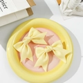 Detail of two yellow silk ribbon bow hair clips on a ceramic plate for girls - Yellow