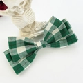 Detail of green and white gingham bow hair clip held by a creative skeleton hand stand - Green