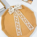 Detailansicht der weißen Spitzen-Haarschleife mit Blumenband auf Korktablett - Beige