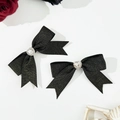 Detail von eleganten schwarzen Strass-Herz-Bogen-Haarspangen mit Goldglitzereffekt - Schwarz
