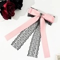Makrodetail der rosa Satinschleife mit schwarzer Spitze, Herz-Strass und langen Bändern - Rosa