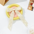 Dettaglio di un elegante fermaglio per capelli in pizzo crema con nastri - Beige