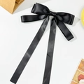 Detail van elegante zwarte satijnen haarstrik met lange vloeiende linten op wit - Zwart