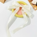Detail van de elegante crème satijnen strik haarclip op een minimalistisch decoratief dienblad - Beige