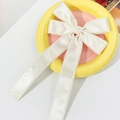 Elegante pinza para el pelo con lazo de satén blanco crema y cintas en un plato decorativo - Beige