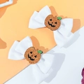 Close-up of white Halloween hair bows featuring sparkly orange sequined pumpkin centers - White Strap Style