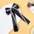 Detail of a black satin bow hair clip with white checkered lace edges and long ribbons - Black