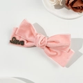Detail van roze fluwelen strik haarspeld met zwarte metalen Love-decoratie erop - Roze