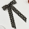 Detail of a large black bow hair clip with leopard heart print and long flowing streamers - Black