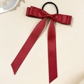 Detail view of a deep red satin ribbon bow hair tie with long streamers on a beige surface - Light Wine Red