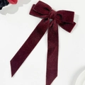 Detalle del lazo de pelo en terciopelo rojo oscuro con cintas largas y textura fina - Burdeos