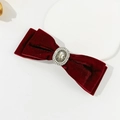 Detailed close-up of dark red velvet bow hair clip with central pearl and engraved ornament - Burgundy