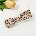 Close-up of leopard print bow hair clip with pink hearts on a ceramic display tray - Apricot