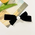 Detailed close-up of a black velvet bow hair clip featuring a glossy center pearl decoration - Black