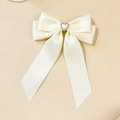 Détail d'une barrette à nœud en ruban crème avec un centre en strass en forme de cœur - Beige