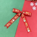 Detail der roten Weihnachtsschleife mit Weihnachtsmann, Schneeflocken und HO HO Motiven - Rot