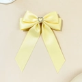 Dettaglio di un fermaglio per capelli in raso giallo pallido con strass a cuore al centro - Giallo