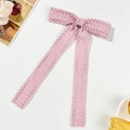 Flat lay of pink lace bow hair clip with ribbons, lace edges, and decorative flowers - Pink