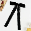 Detail of elegant black lace bow hair clip with long ribbons and intricate mesh texture - Black