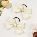 Detalle de dos coleteros de satén crema con perla central y lazos de estilo coreano - Beige