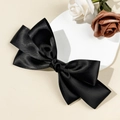 Detail of elegant black satin triple-layered bow hair clip on a decorative white plate - Black