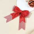 Detalle de un pasador de pelo con lazo rojo de satén y estampado de cuadros sobre fondo beige - Rojo