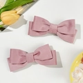 Détail de pinces à cheveux à double nœud en velours côtelé rose sur fond blanc pur - Rose