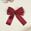 Detail of elegant wine red satin bow hair clip with long ribbons on cream background - Burgundy