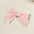 Dettaglio di un fermaglio per capelli a fiocco in velluto rosa con texture morbida e cuciture - Rosa