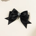 Macro shot of elegant black satin bow hair clip with a sparkling heart-shaped rhinestone - Black