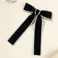 Detalle de lazo grande negro con bordes de encaje festoneado blanco y textura de tela fina - Lazo de Cola Larga Festoneado (Pinza de Pico de Pato)