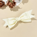 Macro detail of elegant cream satin bow hair clip with pointed swallowtail ends - Beige